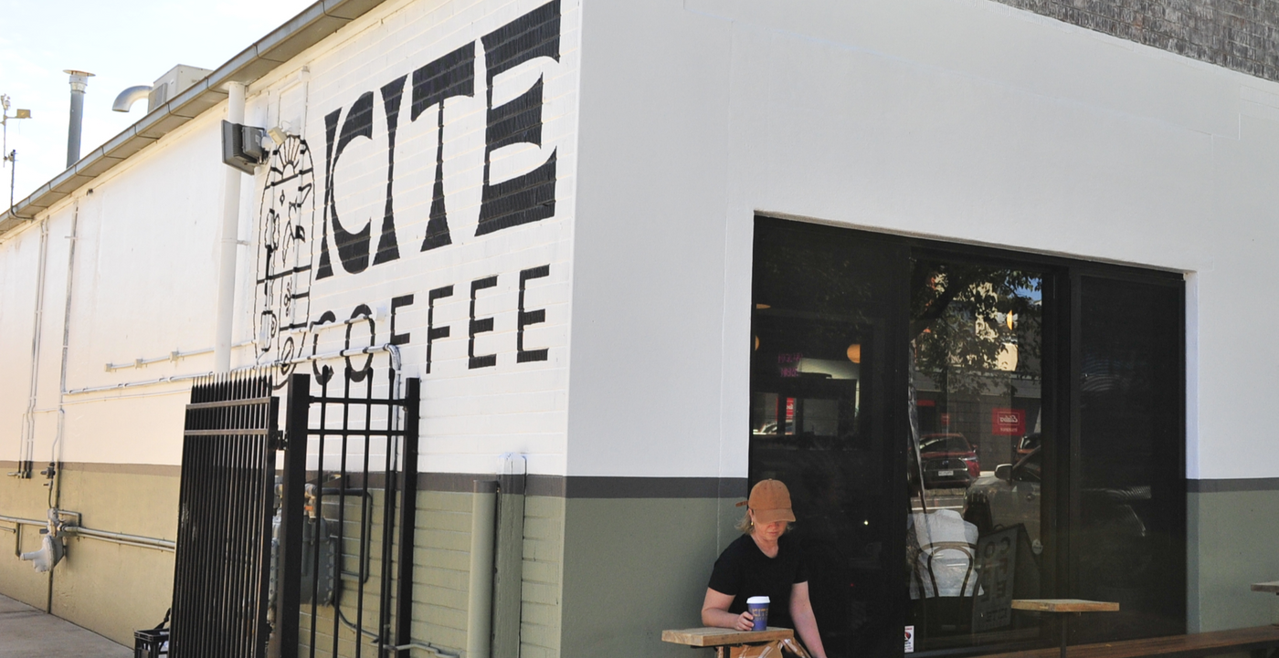 Kite Coffee coffee shop exterior with a person sitting outside.